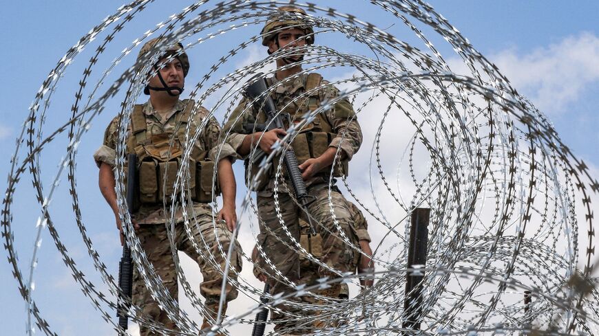 Lebanese army soldiers stand behind barbed wire fence demarcating the Blue Line, near the village of Kfar Shuba, southern Lebanon, June 11, 2023. 