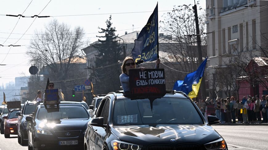 People hold placards as they ride in a convoy of vehicles during a rally held by relatives and friends of Ukrainian prisoners of war, as they call for their exchange with Russian prisoners, in Kyiv on March 9, 2025. 
