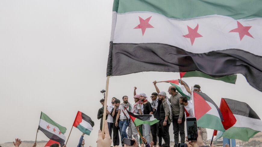 People wave the flag of Palestine and the new flag of Syria as Syrians gather in a protest dubbed "Syrians Against the Occupation" to denounce Israel's continued war on Gaza as well as its occupation of parts of Syria and Palestine in Damascus, Syria, on April 7, 2025.