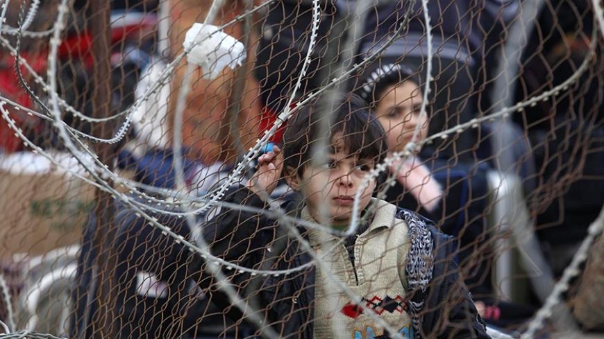 A Palestinian boy waits with his family, hoping to cross into Egypt, at Rafah crossing between Egypt and the southern Gaza Strip February 4, 2014. Egyptian authorities partially opened the Rafah crossing, Gaza's main window to the world, on Tuesday for three days, Palestinian border officials said. Since July 2013, the authorities have kept the crossing largely closed; only opening it partially for humanitarian purposes. REUTERS/Ibraheem Abu Mustafa (GAZA - Tags: POLITICS SOCIETY IMMIGRATION TPX IMAGES OF T