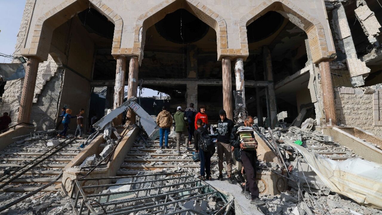 A man walks with salvaged religious books among the rubble of a mosque following Israeli bombardment in Rafah A man walks with salvaged religious books among the rubble of a mosque following Israeli bombardment in Rafah