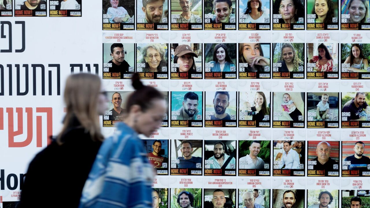 Women pass by a wall covered with photos of hostages that were kidnaped to the Gaza Strip during Hamas deadly attack on Jan. 6, 2025 in Kfar Saba, Israel.